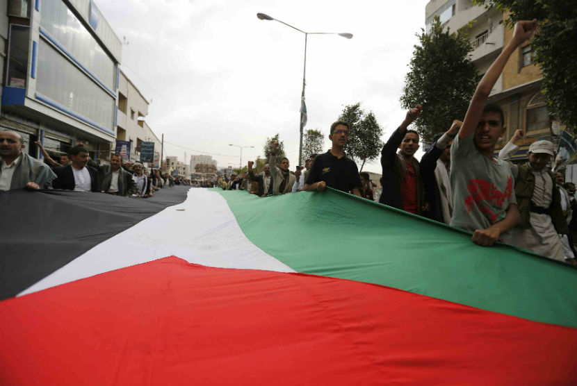 Warga menggelar bendera raksasa Palestina dalam aksi protes menentang serangan udara Israel di Sanaa pada Kamis (10/7). 