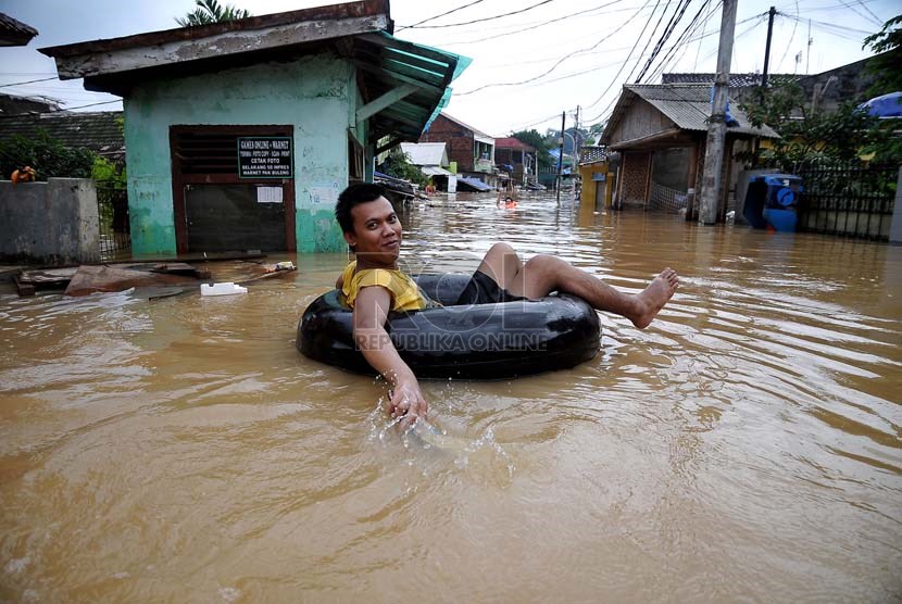  Warga menggunakan ban karet mencoba melintasi banjir luapan air sungai Ciliwung di Jalan H Bawah, Kelurahan Kebon Baru, Kecamatan Tebet, Jakarta Selatan, Rabu (22/1).   (Republika/Prayogi)