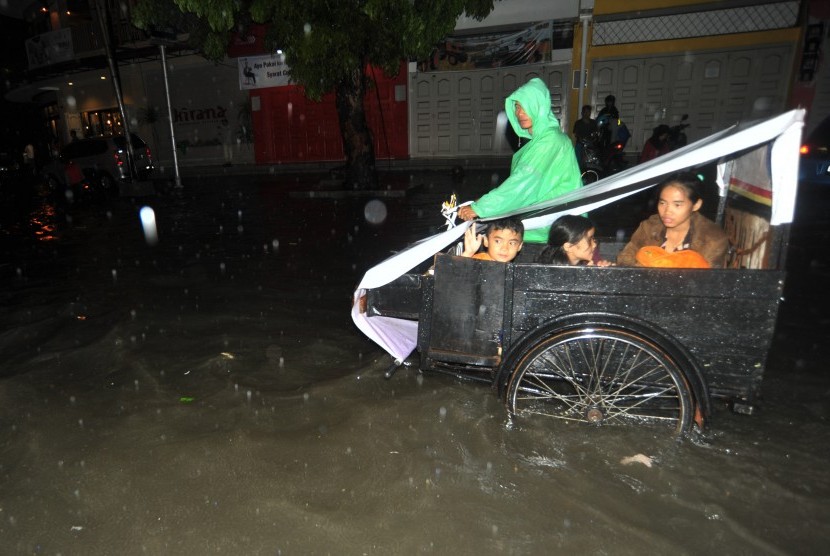 Warga menggunakan becak melintasi banjir di Jl Imam Bonjol, Padang, Sumatera Barat, Sabtu (9/9). Banjir bandang juga terjadi di wilayah Solok Selatan