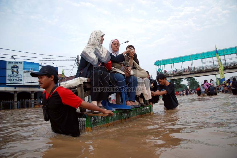   Warga menggunakan gerobak untuk melintasi genangan air banjir yang merendam Jalan KH Abdullah Syafe'i, Kp melayu Besar, Jakarta, Jumat (18/1).  (Republika/Prayogi)
