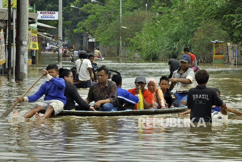 Warga menggunakan jasa perahu kayu untuk menerobos banjir yang merendam di Jalan Raya Banjaran di Kelurahan Andir, Kecamatan Baleendah, Kabupaten Bandung, Rabu (8/3).