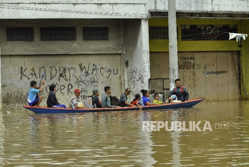 Warga menggunakan jasa perahu kayu untuk menerobos banjir yang merendam di Jalan Raya Banjaran di Kelurahan Andir, Kecamatan Baleendah, Kabupaten Bandung, Rabu (8/3).