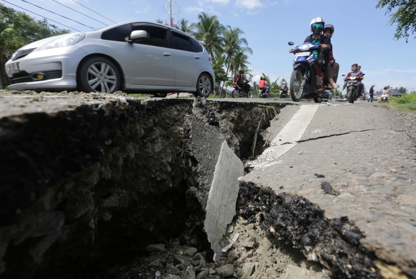 Warga menggunakan kendaraan melaju di jalanan yang rusak akibat gempa 6.5 SR, di Meuredu, Pidie Jaya, Aceh, Rabu (7/12). 