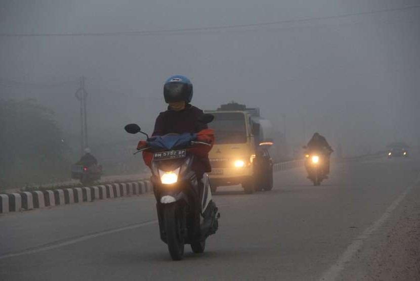  Residents use masks when passing on the road covered in smoke haze in the city of Dumai, Dumai, Riau, Thursday (Aug 16).