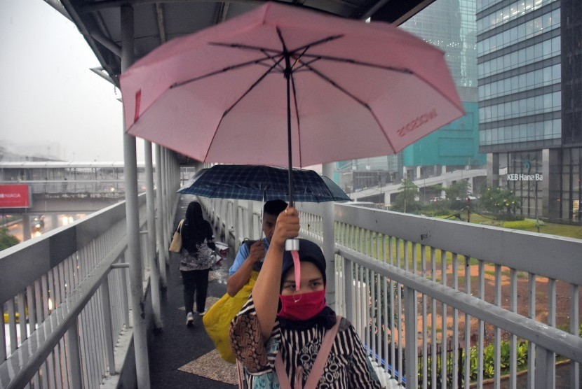 Warga menggunakan payung saat hujan mengguyur kawasan Gatot Subroto, Jakarta, Senin (11/2/2019). 