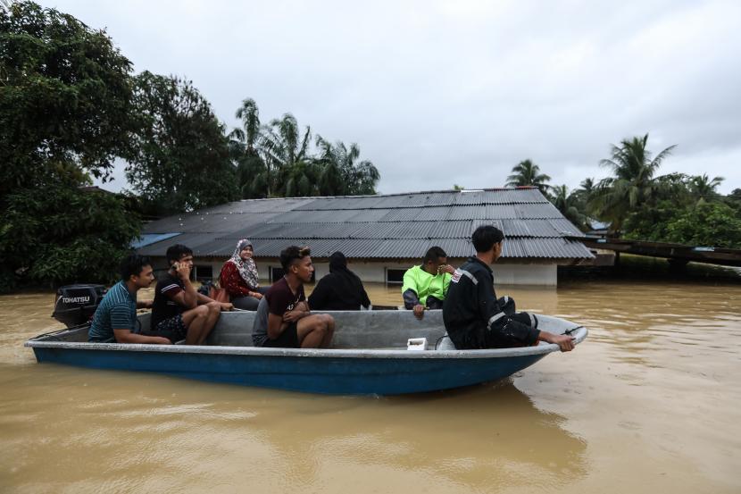 Warga menggunakan perahu melewati kawasan banjir di Kuala Terengganu, Malaysia, 21 Desember 2022. Menurut pihak berwenang Malaysia, lima orang tewas dan lebih dari 70.000 dievakuasi setelah musim hujan memicu banjir yang menggenangi negara bagian Kelantan, Terengganu, dan Pahang.