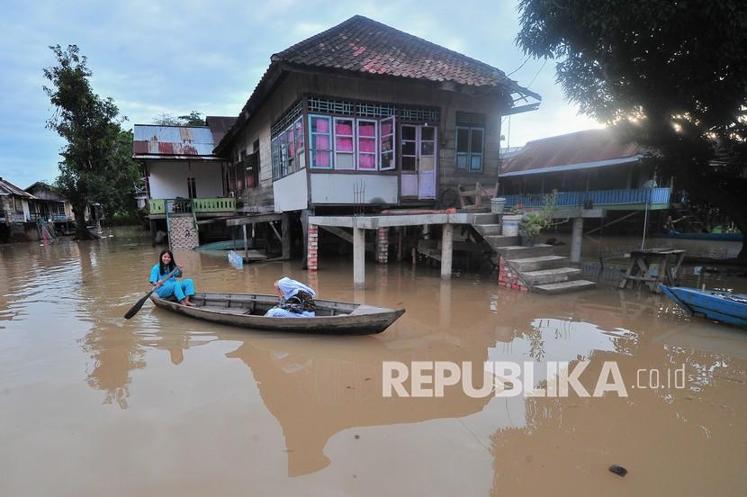 Warga menggunakan perahu melintasi kawasan permukiman yang tergenang banjir luapan Sungai Batanghari di Legok, Danau Sipin, Kota Jambi, Provinsi Jambi, Kamis (11/11/2021). 