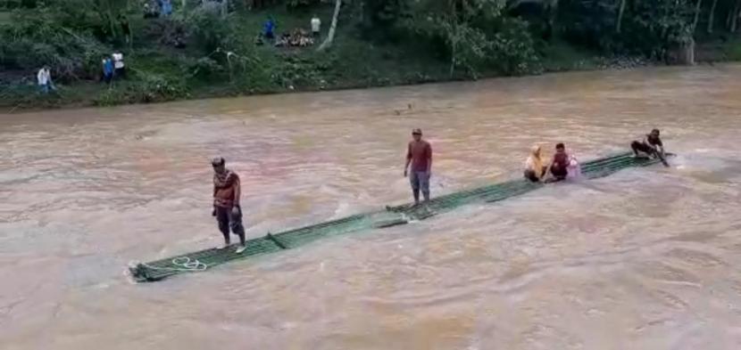Warga menggunakan rakit untuk melintasi Sungai Cimedang, Kecamatan Cikatomas, Kabupaten Tasikmalaya, lantaran jembatan antardesa di wilayah itu terputus diterjang banjir bandang. 