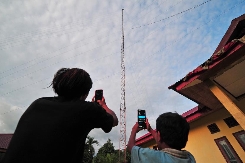 Warga menggunakan telepon genggam untuk menikmati akses internet gratis di kantor desa. Dari total 1.842 desa di Sulteng, 850 desa belum memiliki akses internet. Ilustrasi.
