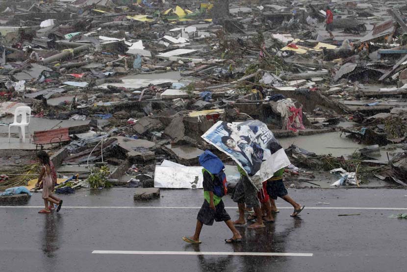  Warga menggunakan terpal untuk melindungi mereka dari hujan saat topan melanda kota Tacloban di provinsi Leyte, Filipina tengah, Ahad (10/11).  (AP/Bullit Marquez)