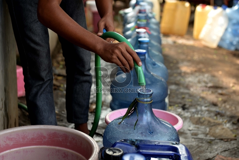 Warga mengisi air bersih ke sebuah galon dari sumur pompa 