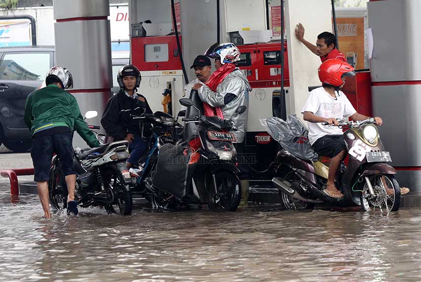 Warga mengisi BBM di SPBU yang tergenang air saat banjir yang merendam jalan Gunung Sahari, Jakarta Pusat, Kamis (27/2).     (Republika/Yasin Habibi)