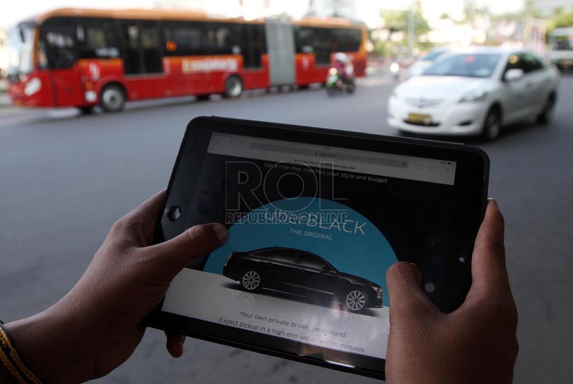   Warga mengoperasikan aplikasi taksi uber via internet, Jakarta, Jumat (22/8). (Republika/ Yasin Habibi)