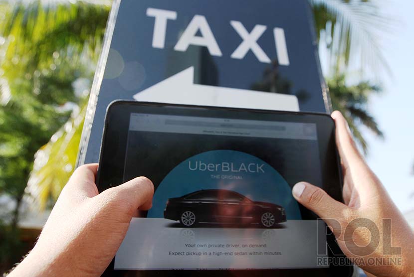 Warga mengoperasikan aplikasi taksi uber via internet, Jakarta, Jumat (22/8). Pemprov DKI menggolongkan layanan taksi mewah yang ditawarkan Uber sebagai taksi gelap sehingga melarangnya beroperasi.