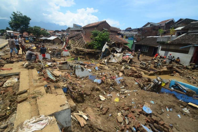 Warga mengumpulkan barang-barang dari puing bangunan rumah yang roboh akibat diterjang banjir bandang aliran Sungai Ciamanuk di Kampung Cimacan, Kecamatan Tarogong, Kabupaten Garut, Jawa Barat, Rabu (21/9). 