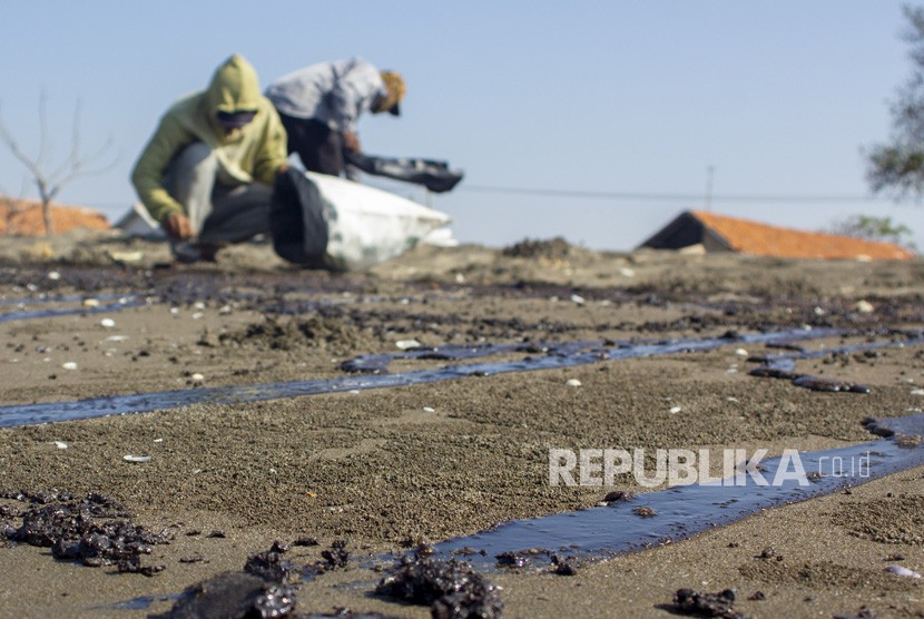 Warga mengumpulkan tumpahan minyak (Oil Spill) yang tercecer di Pesisir Pantai Cemarajaya, Karawang, Jawa Barat, Senin (22/7/2019). 
