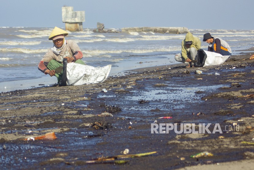Warga mengumpulkan tumpahan minyak (Oil Spill) yang tercecer di Pesisir Pantai Cemarajaya, Karawang, Jawa Barat, Senin (22/7/2019).