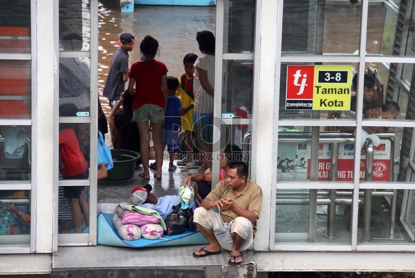  Warga mengungsi di Halte Bus Transjakarta Taman Kota di Jalan Daan Mogot, Jakarta Barat, Ahad (19/1). ( Republika/Yasin Habibi)