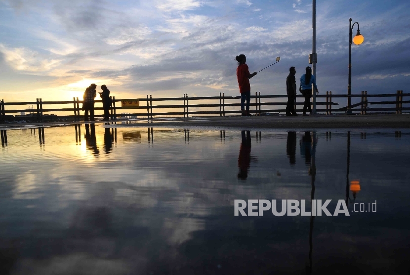 Warga menikmati matahari tenggelam saat menunggu berbuka puasa (ngabuburit) di Pantai Festival, Ancol, Jakarta, Kamis (30/6).  (Republika/Agung Supriyanto)