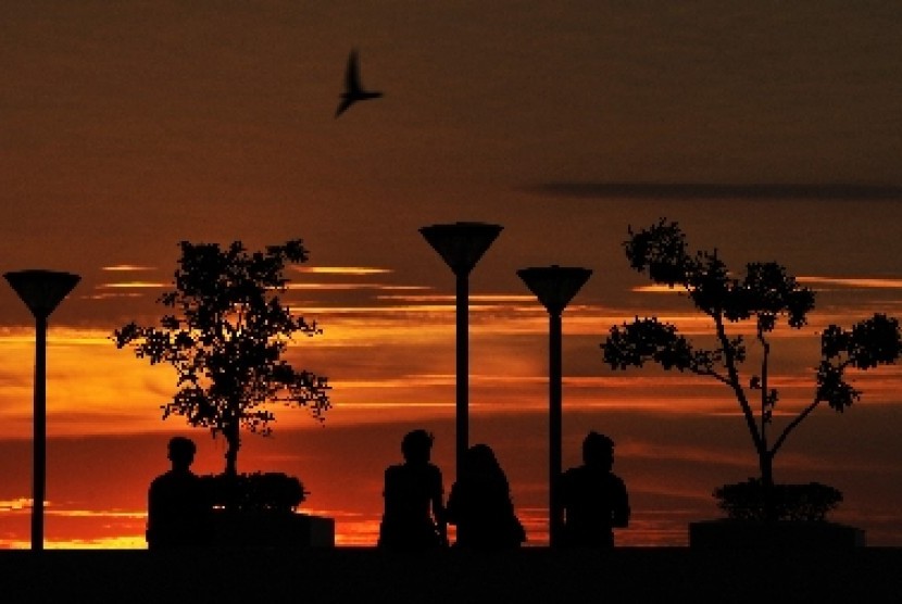 Warga menikmati suasana terbenamnya matahari (sunset) di Pantai Losari Makassar, Sulawesi Selatan, Senin (22/6).