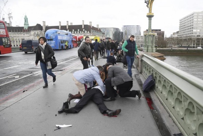 Warga menolong korban terluka di Westminster Bridge, London, Rabu (22/3). Lima orang tewas dan 40 luka dalam serangan di parlemen Inggris.