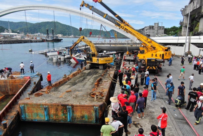 Warga menonton operasi penyelamatan korban ambruknya jembatan di Nanfangao, Taiwan, Selasa (1/10). 