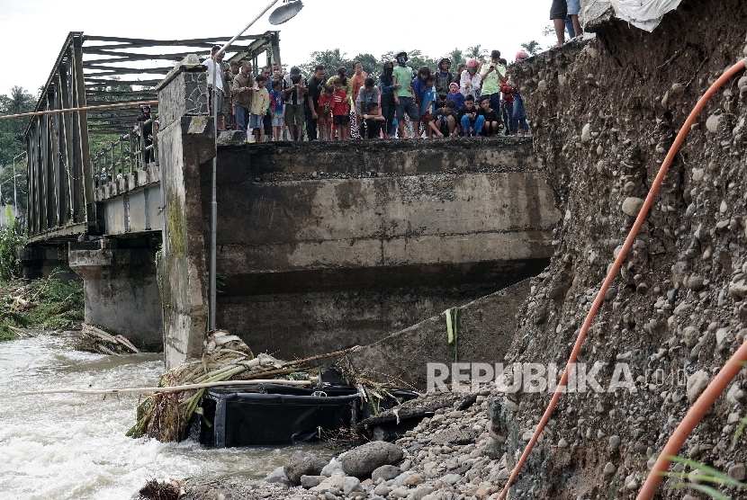 Warga menonton oprit atau sambungan antara jalan dengan jembatan Kali Klawing, yang ambles akibat tergerus aliran air, di Desa Majapura, Bobotsari, Purbalingga, Jateng, Minggu (19/3).