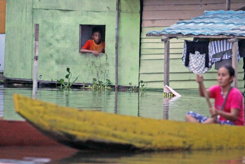 Warga menunggu air surut menyusul banjir yang menggenangi rumah dengan ketinggian 1 meter di Kelurahan Tabumela, Kabupaten Gorontalo, Gorontalo, Minggu (30/10). 