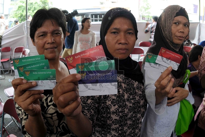 Warga menunjukan Kartu Indonesia Sehat (KIS), Kartu Keluarga Sejahtera (KKS) dan Kartu Indonesia Pintar (KIP) saat pembagian tiga jenis kartu sakti itu di Kampung Melayu, Jakarta Timur, Rabu (13/5). (Republika/Agung Supriyanto)