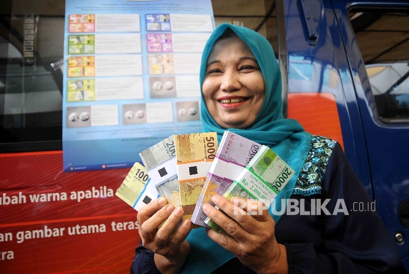  Warga menunjukan uang rupiah baru saat peluncuran uang baru di Blok M Square, Jakarta, Senin (19/12).