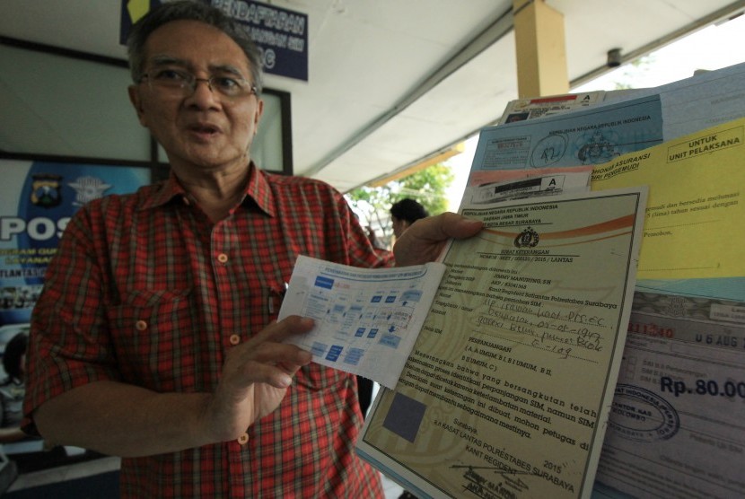  Warga menunjukkan blanko Surat Keterangan Pengganti Surat Ijin Mengemudi (SIM) di Satpas Colombo Surabaya, Jawa Timur, Kamis (6/8).