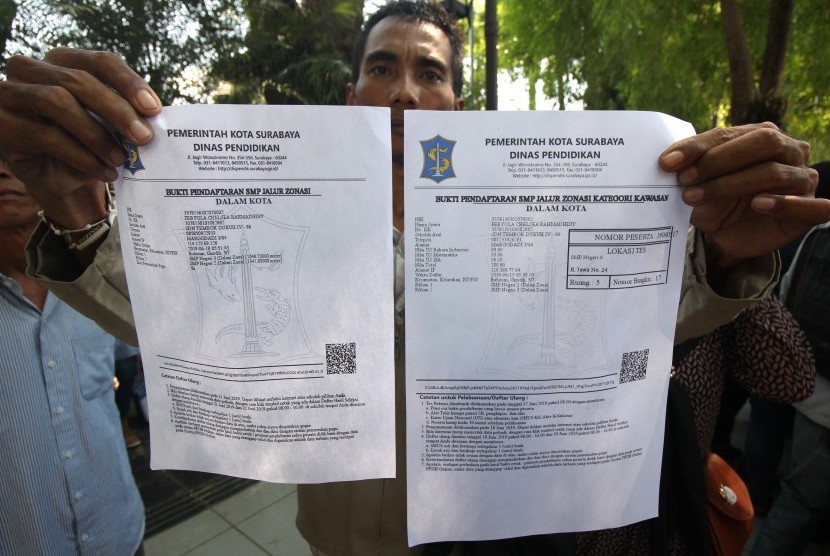 Warga menunjukkan bukti pendaftaran SMP jalur zonasi saat berunjukrasa di Balai Kota Surabaya, Jawa Timur, Rabu (19/6/2019). 