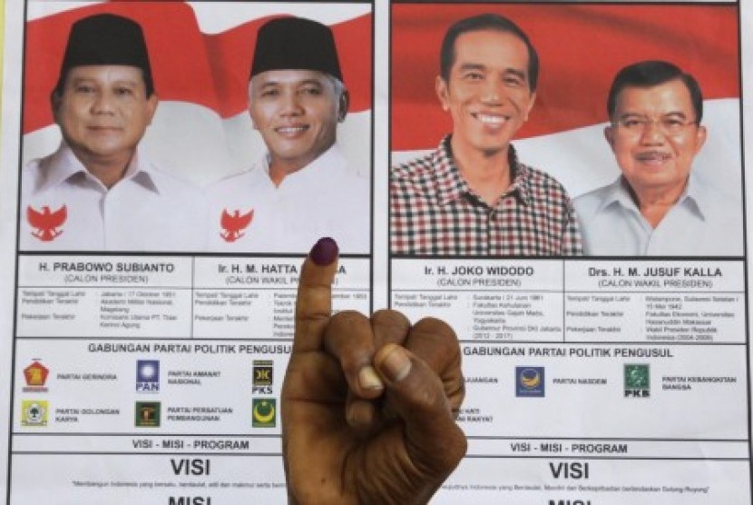 Warga menunjukkan jarinya seusai memberikan hak pilihnya pada pemilihan presiden 2014 