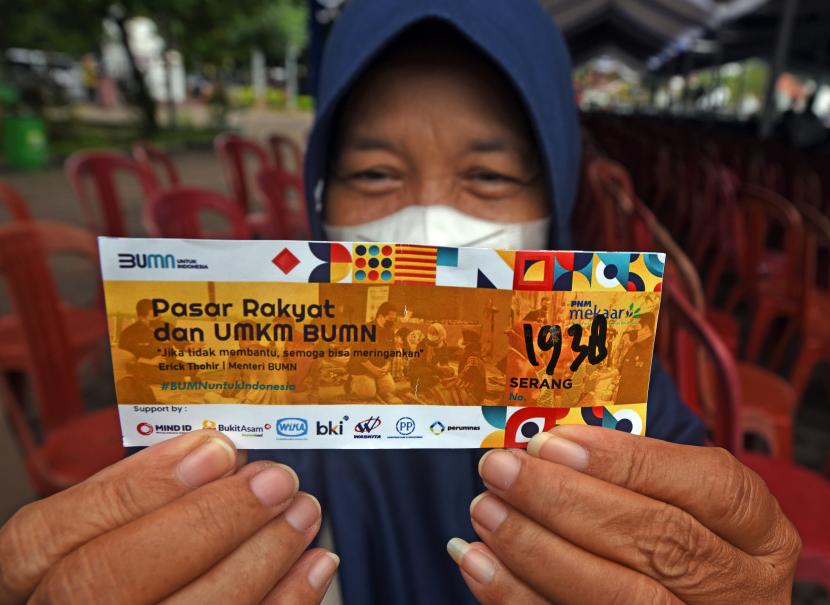 Warga menunjukkan kupon belanja paket sembako di arena bazar murah yang digelar Kementerian BUMN di Alun-alun Serang, Banten, Sabtu (28/5/2022). Kementerian BUMN bekerjasa dengan PT Permodalan Nasional Madani (PNM) Persero menyediakan 4.000 paket sembako murah terdiri dari 5kg beras, 1kg gula dan 1 liter minyak goreng yang dijual seharga Rp65 ribu. 