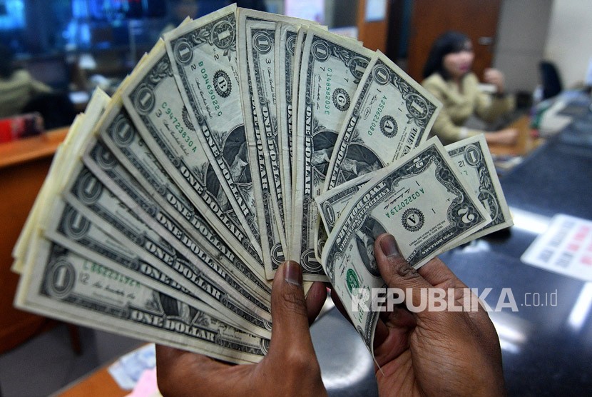 Warga menunjukkan pecahan uang dolar AS yang ditukarkan di salah satu gerai penukaran mata uang asing di Jakarta. ilustrasi