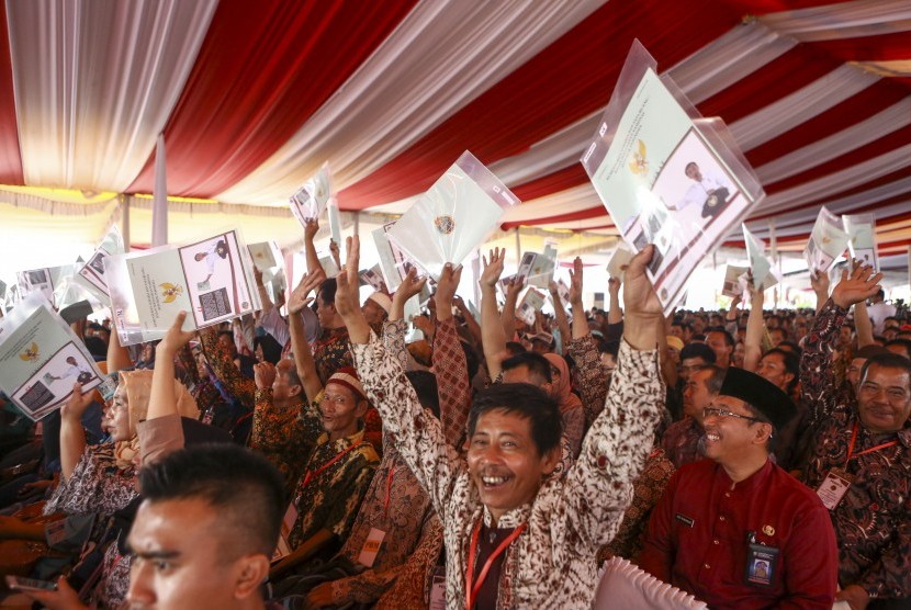 Warga menunjukkan sertifikat tanah saat mengikuti penyerahan sertifikat hak atas lahan tanah oleh Presiden Joko Widodo di pelataran Benteng Kuto Besak (BKB), Palembang, Sumatera Selatan, Jumat (13/7).