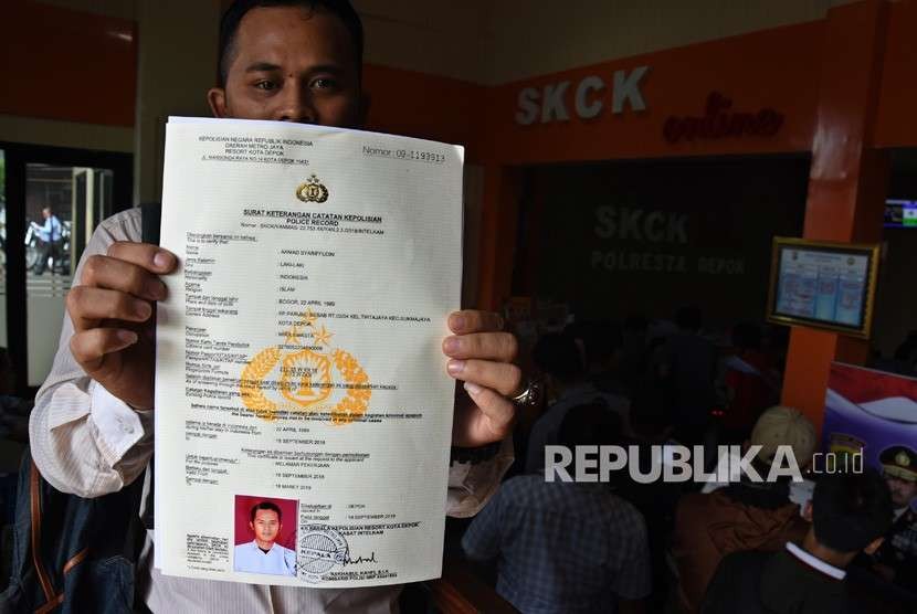 Warga menunjukkan Surat Keterangan Catatan Kepolisian (SKCK) yang telah diproses seusai mengantre di Polresta Depok, Jawa Barat, Selasa (18/9). 