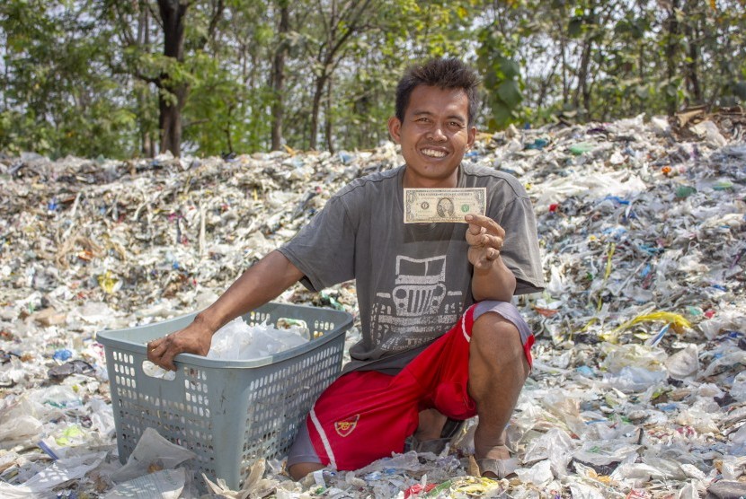 Warga menunjukkan temuan uang dolar Amerika saat memilah sampah plastik di tumpukan sampah impor di Desa Tamansari, Karawang, Jawa Barat, Senin (1/7/2019).