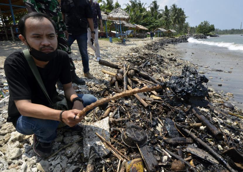 Warga menunjukkan tumpahan limbah minyak yang tercecer di pesisir pantai Sebalang Katibung, Lampung Selatan, Lampung, Jumat (10/9/2021). Tumpahan minyak yang termasuk dalam golongan limbah B3 (Bahan Berbahaya dan Beracun) itu mencemari sejumlah pesisir pantai di Lampung