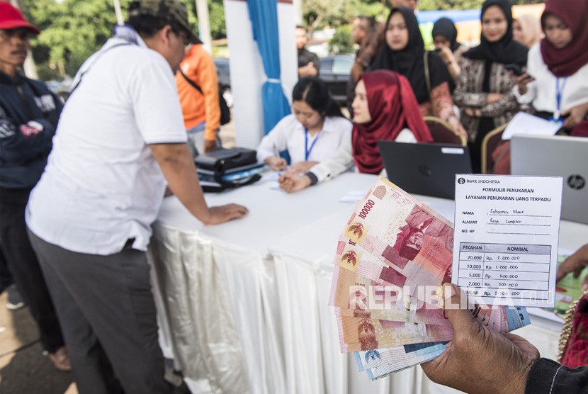 ilustrasi. Warga menunjukkan uang sebelum ditukarkan di loket mobil kas keliling saat pembukaan layanan penukaran uang di Bandung, Jawa Barat, Senin (21/5). 
