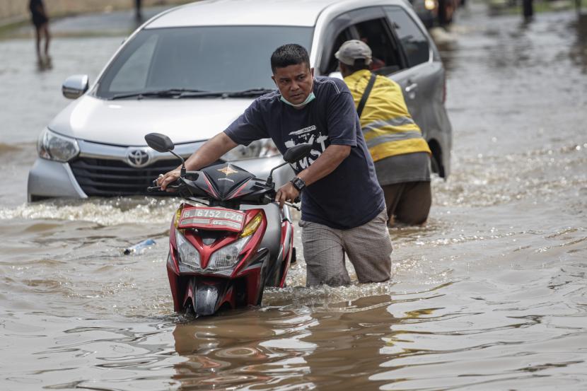 Warga menuntun sepeda motornya saat melewati banjir, ilustrasi