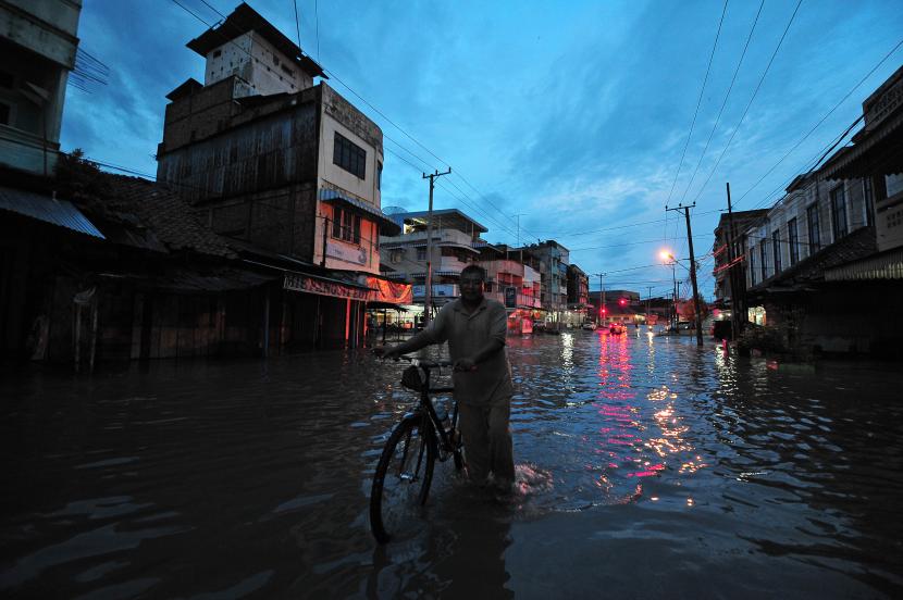 Ilustrasi. Warga menuntun sepeda saat menerobos banjir yang menggenangi Jalan Orang Kayo Hitam setelah diguyur hujan di Jambi. Cuaca Ekstrem akan Landa Jambi Sepekan Mendatang