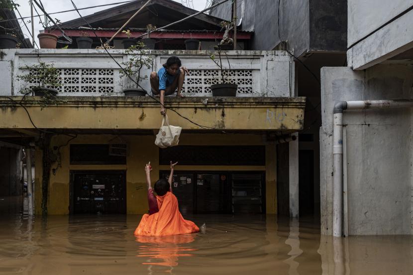Warga menurunkan barang saat banjir di permukiman penduduk kawasan Rawajati, Jakarta, Senin (10/10/2022). BPBD DKI Jakarta pada Senin (10/10) pukul 06.00 WIB mencatat sebanyak 53 RT di DKI Jakarta terendam banjir akibat luapan Sungai Ciliwung. 