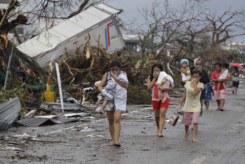 Warga menutup hidung mereka dari bau mayat di kota Tacloban, provinsi Leyte, Filipina tengah,  Ahad (10/11).  (AP/Bullit Marquez)