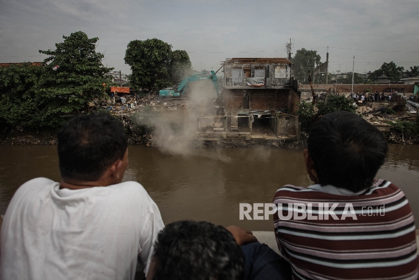 Warga menyaksikan alat berat yang menghancurkan sebuah rumah saat penggusuran di pemukiman proyek normalisasi Sungai Ciliwung, Bukit Duri, Jakarta, Rabu (28/9). 