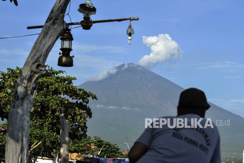 Warga menyaksikan asap putih yang terhembus dari kawah Gunung Agung terlihat dari Amed, Karangasem, Bali, Kamis (7/12). 