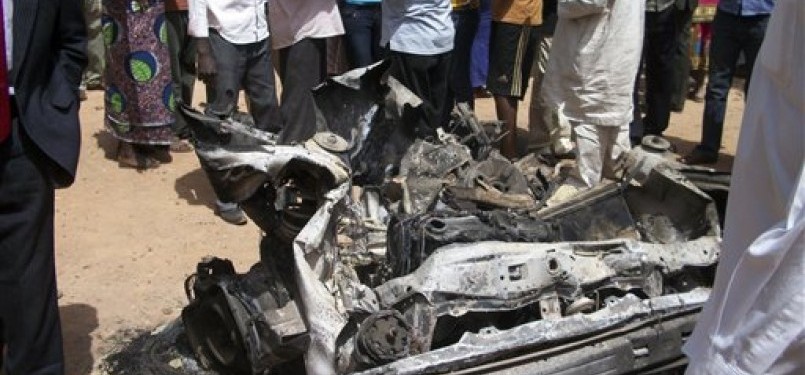 Warga menyaksikan bangkai mobil yang digunakan untuk aksi bom bunuh diri di sebuah Gereja Katholik di Jos, Nigeria, Ahad (11/3).
