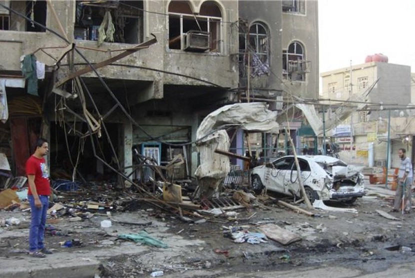Warga menyaksikan bangunan dan mobil yang hancur akibat terkena serangan bom yang terus melanda Irak.
