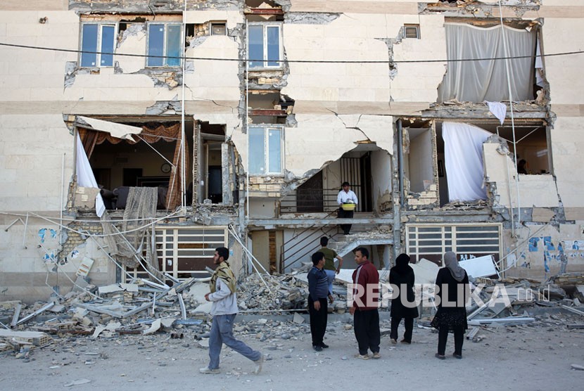Warga menyaksikan bangunan yang hancur akibat gempa di kota Kutub-Zahab di Provinsi Kermanshah, Iran, Senin (13/11). Gempa berkekuatan 7,2 besar melanda wilayah tersebut di sepanjang perbatasan antara Iran dan Irak pada (12/11), menewaskan sedikitnya 129 orang dan melukai lebih dari 300.