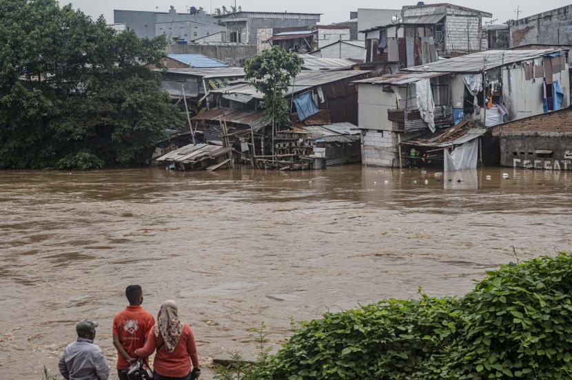 Warga menyaksikan deretan permukiman bantaran Sungai Ciliwung yang terendam banjir di Jakarta, Senin (10/10/2022).